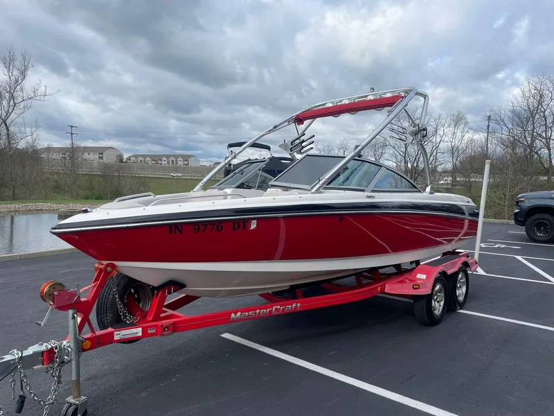 Slide: The Image of 2005 MasterCraft X-10 red and white boat on trailer in parking lot. - 6