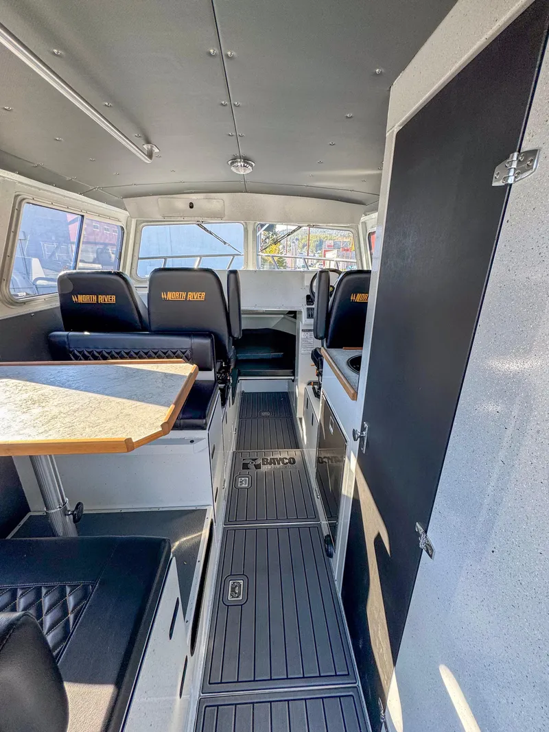 Slide: The Image of 2024 North River Endurance 2800EXL boat interior with seating and table. - 2