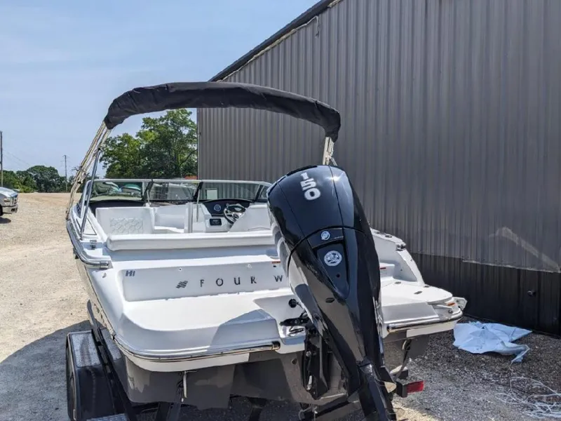 Slide: The Image of 2023 Four Winns H1 OB boat with outboard motor, parked outdoors. - 3