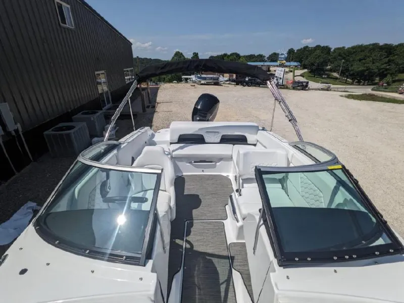 Slide: The Image of 2023 Four Winns H1 OB boat with open deck and seating, parked outdoors. - 5