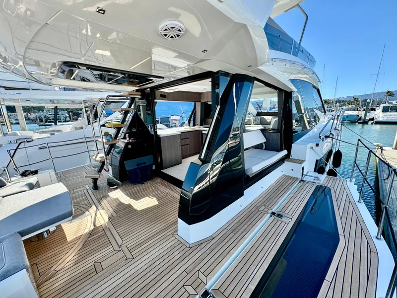 Slide: The Image of 2025 Galeon 500 Fly yacht with modern deck and luxurious seating at a marina. - 13