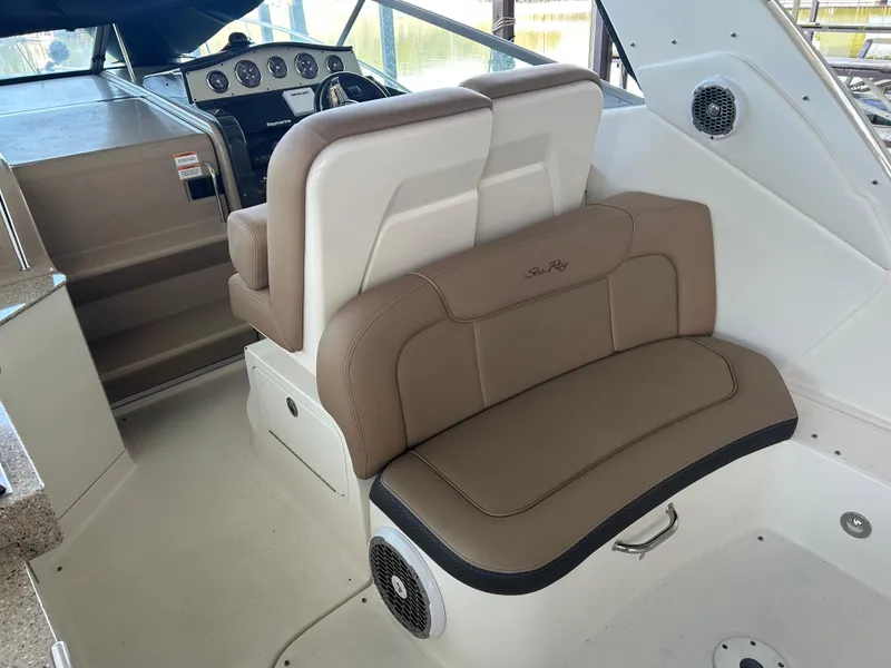 Slide: The Image of 2016 Sea Ray 330 Sundancer interior with beige seating and dashboard controls. - 36