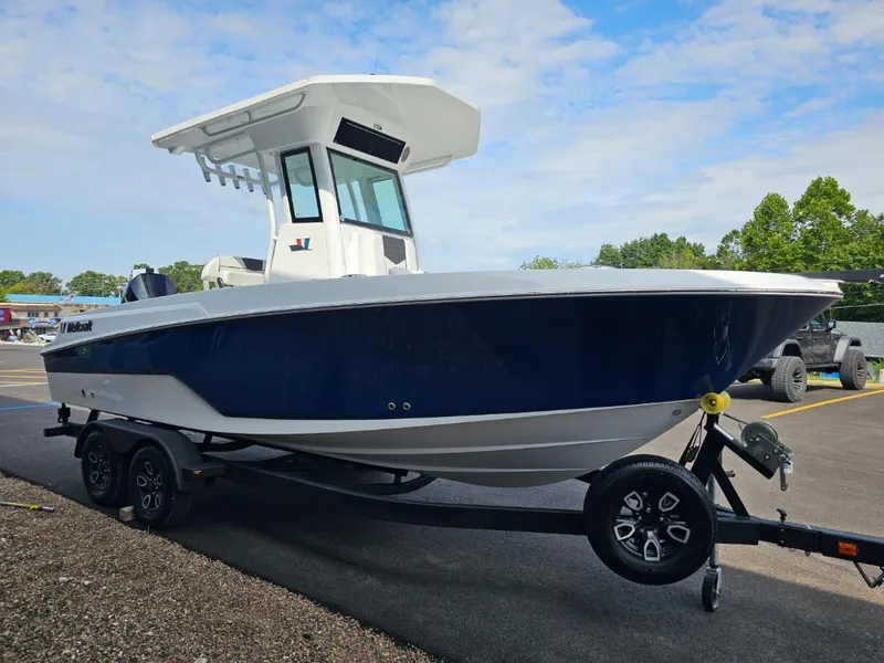 Slide: The Image of 2025 Wellcraft 223 Fisherman boat on trailer, blue and white design, parked outdoors. - 5
