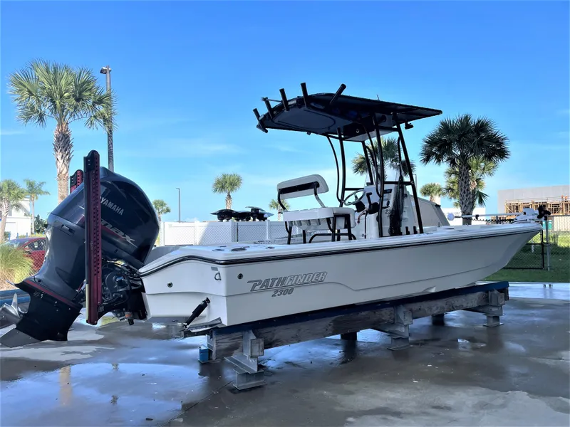Slide: The Image of 2017 Pathfinder 2300 HPS boat on a stand with palm trees in the background. - 0