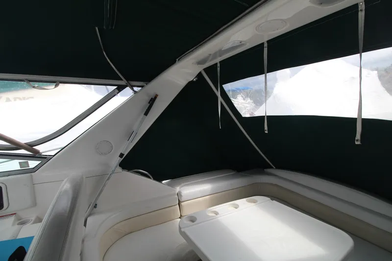 Slide: The Image of 1998 Wellcraft 3200 Martinique boat interior with seating and table, featuring dark canopy. - 12