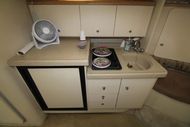 Slide: The Image of 1998 Wellcraft 3200 Martinique boat kitchenette with sink, stove, and mini fridge. - 21