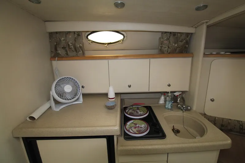 Slide: The Image of 1998 Wellcraft 3200 Martinique boat kitchen with stove, sink, and fan. - 22