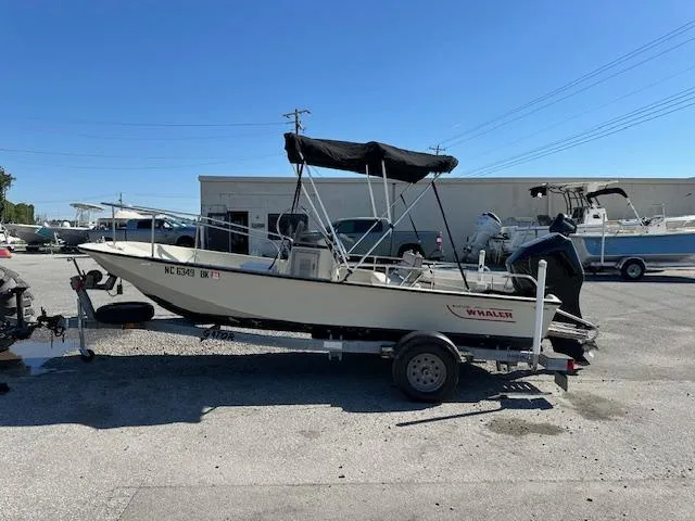 The Image of 1987 Boston Whaler 17 Montauk boat on a trailer in a parking lot. - 0