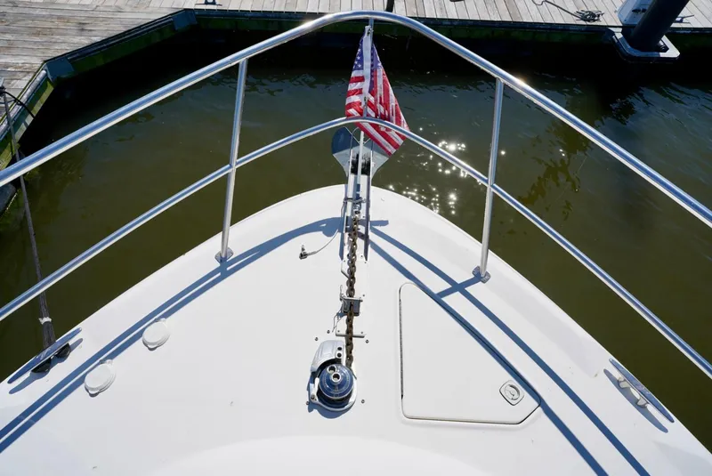 Slide: The Image of Bow of 2002 Sea Ray 480 Sedan Bridge with American flag at dock. - 20