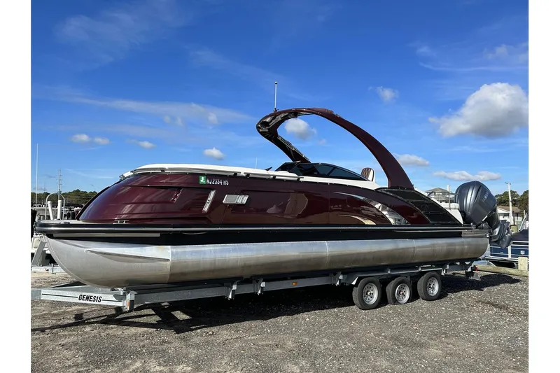 The Image of 2021 Bennington QX 25 Swingback pontoon boat on a trailer under a clear blue sky. - 1