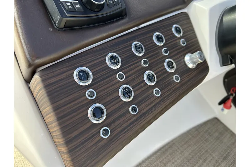 Slide: The Image of Control panel of a 2021 Bennington QX 25 Swingback boat with wood finish and buttons. - 22