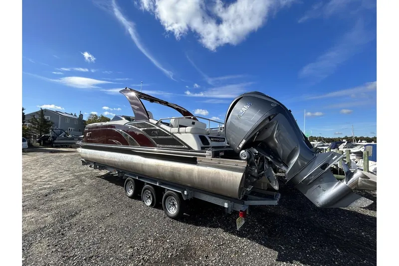 Slide: The Image of 2021 Bennington QX 25 Swingback pontoon boat on a trailer under a clear blue sky. - 3