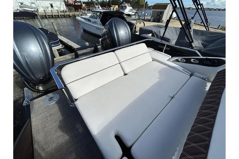 Slide: The Image of 2021 Bennington QX 25 Swingback boat with dual outboard motors at a marina. - 32