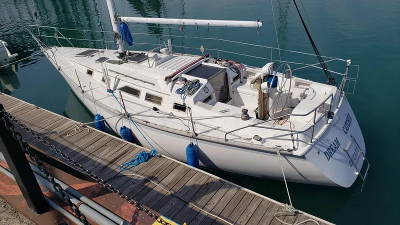 The Image of 1983 Hunter 34 sailboat docked at a marina, featuring a sleek white design. - 0