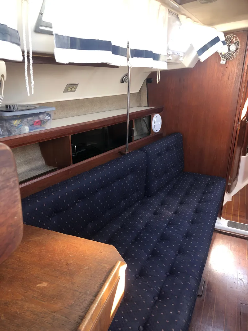 Slide: The Image of Interior of 1983 Hunter 34 sailboat with blue cushioned seating and wooden accents. - 15