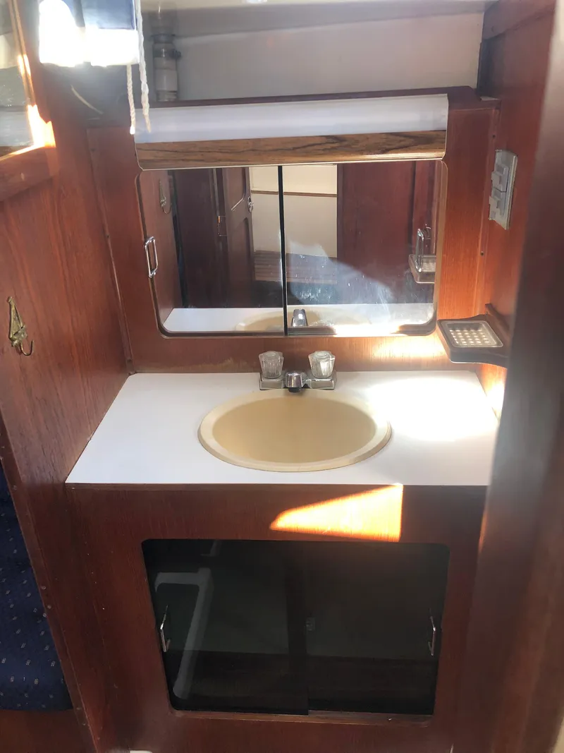 Slide: The Image of 1983 Hunter 34 yacht bathroom with sink, mirror, and wooden cabinetry. - 18