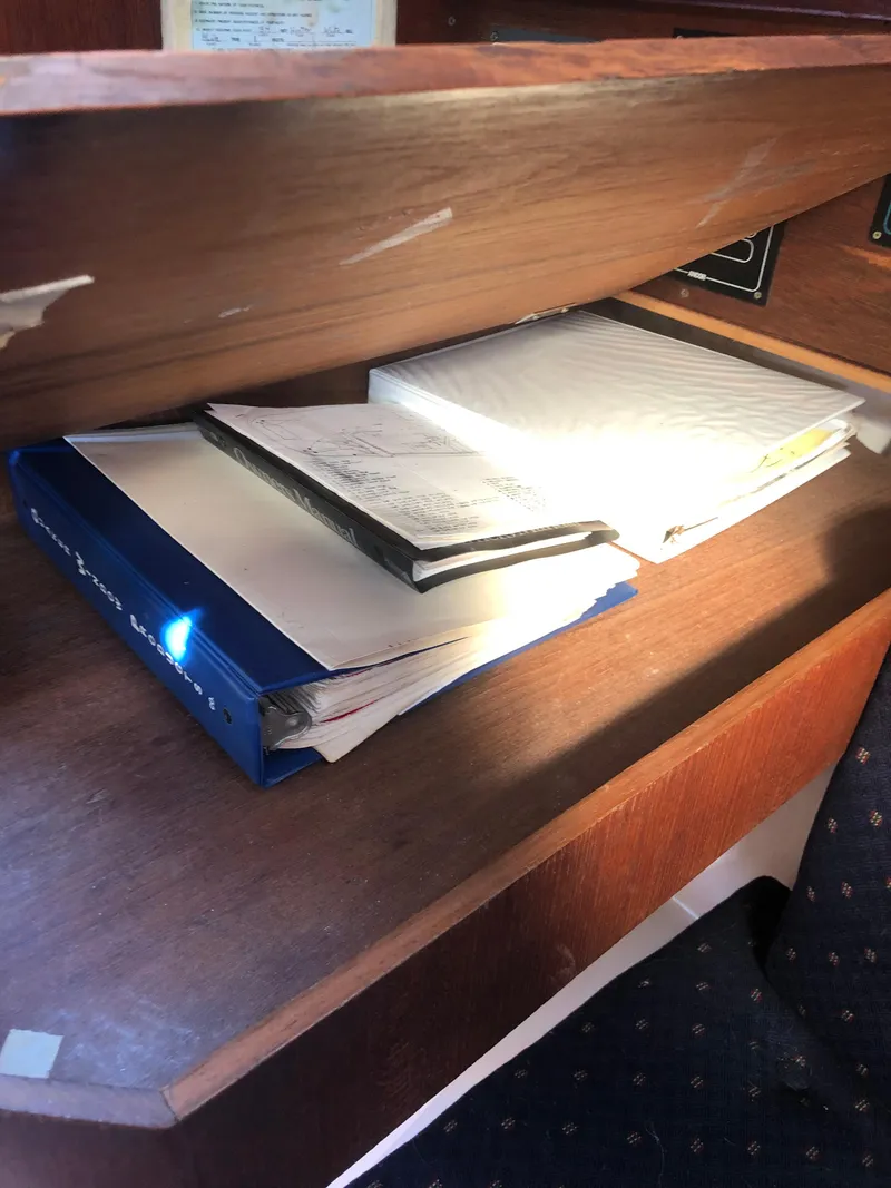 Slide: The Image of Wooden shelf with books and papers inside a 1983 Hunter 34 sailboat. - 28