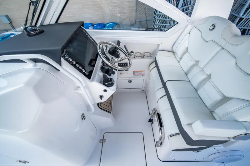 Slide: The Image of 2024 Edgewater 262 CX boat cockpit with steering wheel and cushioned seating. - 14