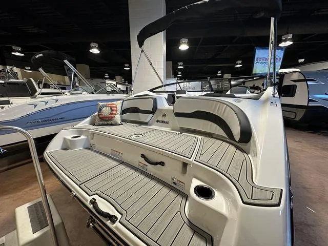 Slide: The Image of 2024 Yamaha Boats SX195, rear view, showcasing spacious deck and seating in showroom. - 6