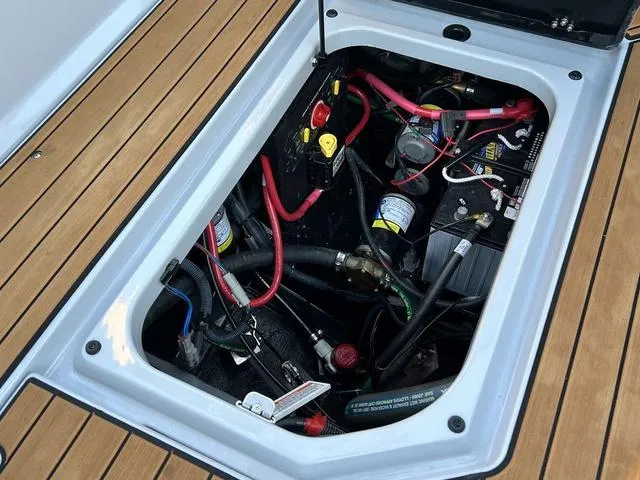 Slide: The Image of 2022 Nautique G23 engine compartment with wiring and components on teak deck. - 16
