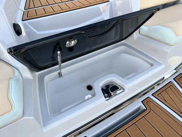 Slide: The Image of 2022 Nautique G23 boat storage compartment with open lid and teak flooring. - 26