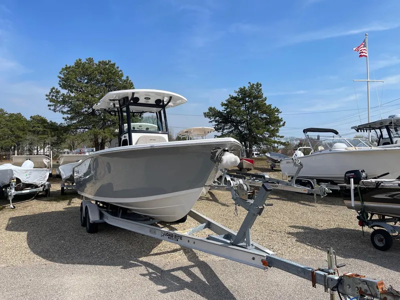 Slide: The Image of 2024 Sea Pro 242 Center Console boat on a trailer in a marina. - 2