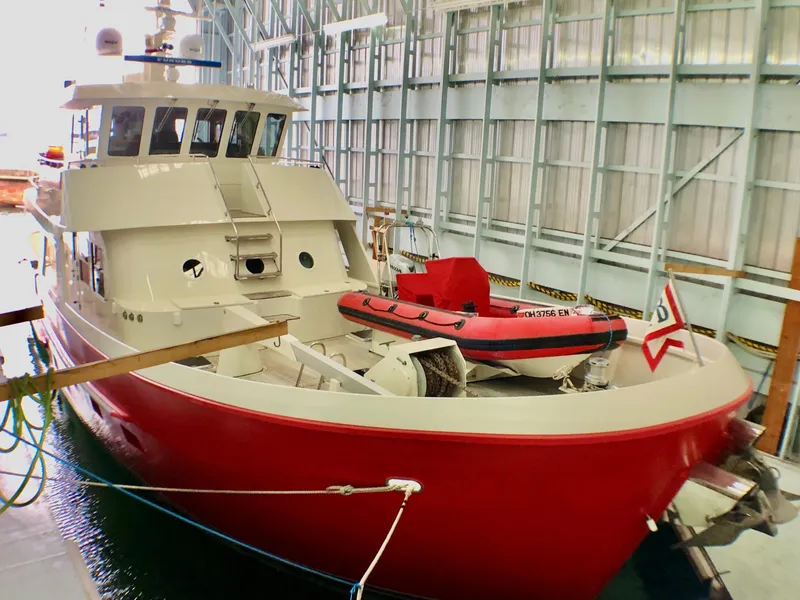 Slide: The Image of Red and white 2002 North Sea Trawler docked indoors with a small boat on deck. - 6