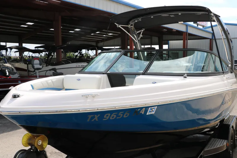 Slide: The Image of 2021 Regal 2000 ESX Bowrider boat in blue and white, docked in a marina. - 10