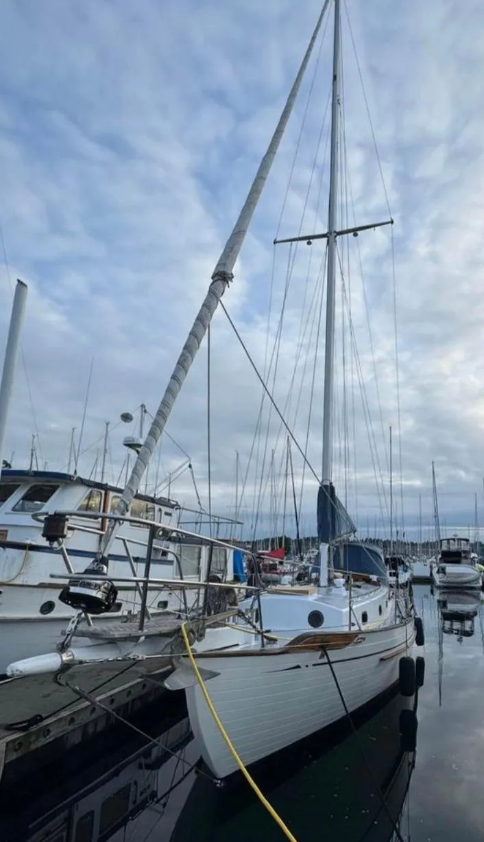 The Image of 1977 Tayana 37 sailboat docked at a marina under a cloudy sky. - 0