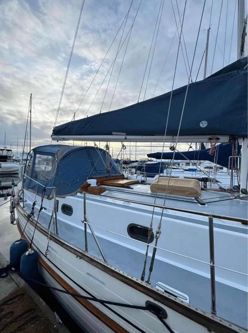 Slide: The Image of 1977 Tayana 37 sailboat docked at marina under cloudy sky. - 2