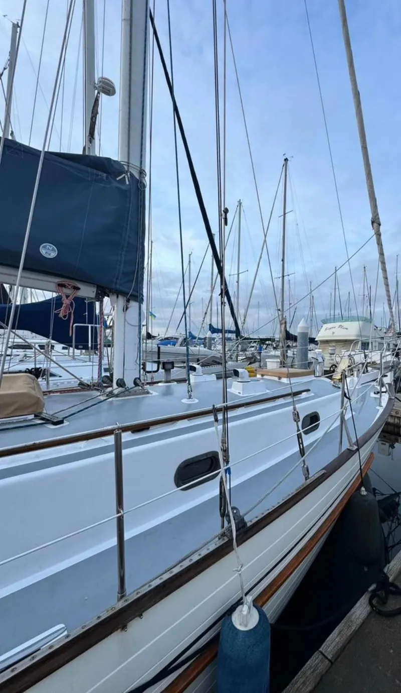 Slide: The Image of 1977 Tayana 37 sailboat docked at marina, surrounded by other boats under a clear sky. - 3