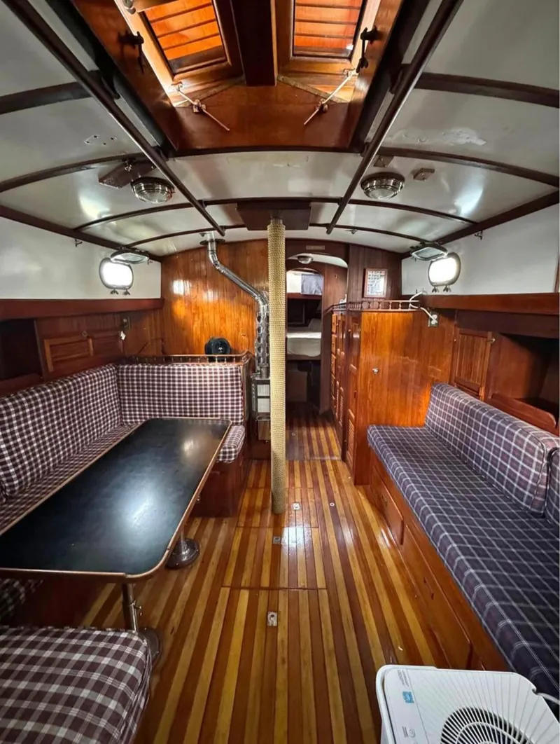 Slide: The Image of Interior of a 1977 Tayana 37 sailboat with wood paneling and plaid seating. - 4