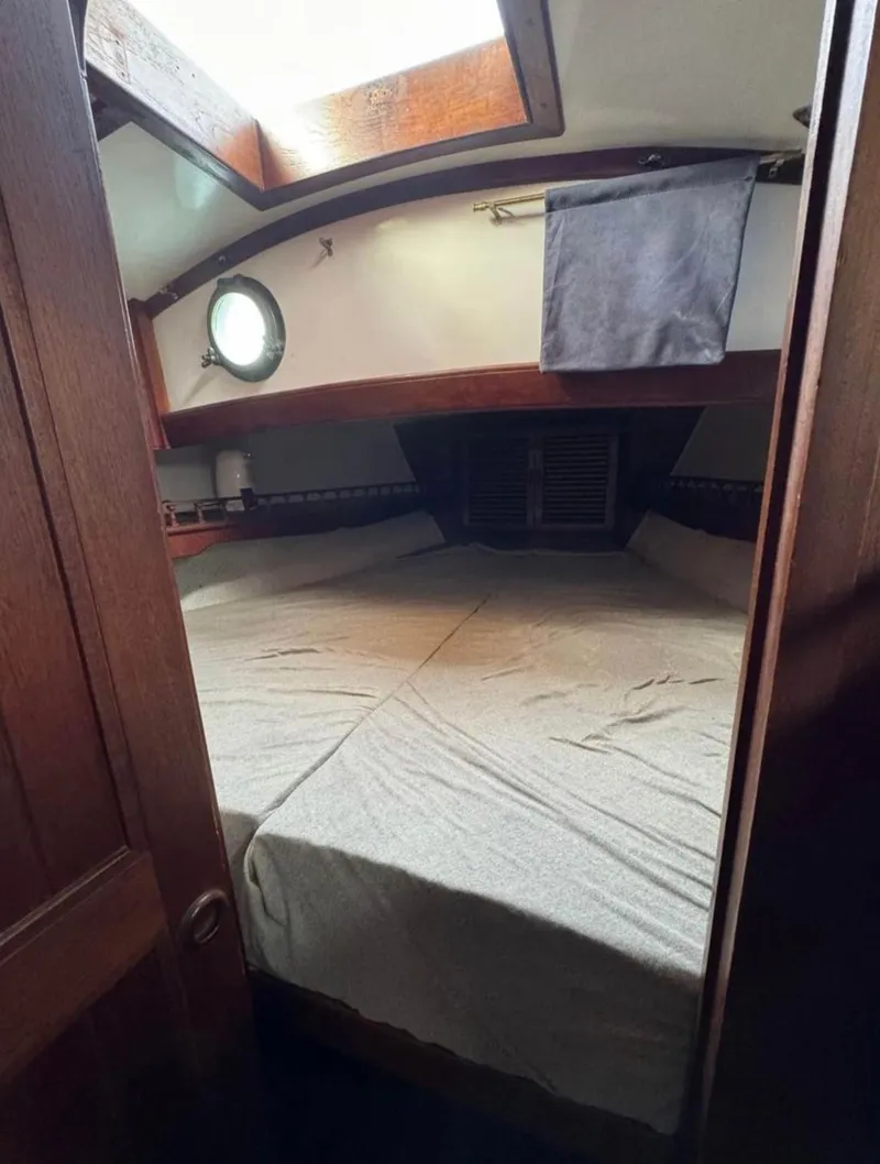 Slide: The Image of 1977 Tayana 37 sailboat cabin with bed, porthole, and wooden interior. - 8