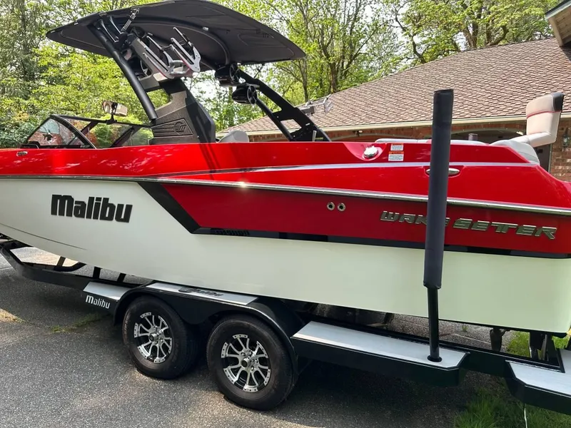 Slide: The Image of 2017 Malibu 24' WAKESETTER MXZ boat on trailer, red and white, parked outdoors. - 4