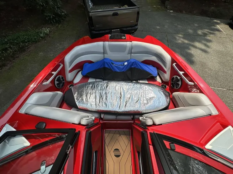 Slide: The Image of 2017 Malibu 24' WAKESETTER MXZ boat with red and white interior, surfboard, and blue life jacket. - 6