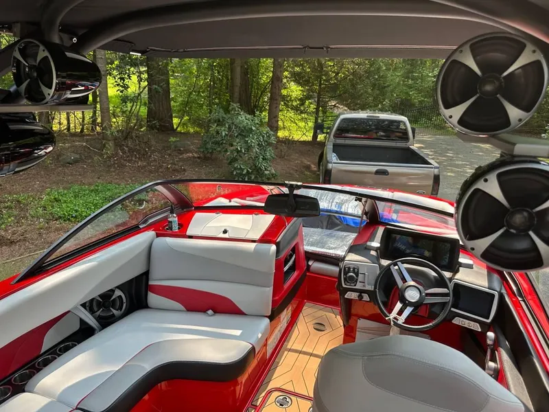 Slide: The Image of 2017 Malibu 24' WAKESETTER MXZ interior with red and gray seating, advanced dashboard, and sound system. - 7