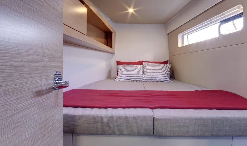 Slide: The Image of Nautitech 40 Open 2016 model cabin with bed, striped pillows, and red blanket. - 11