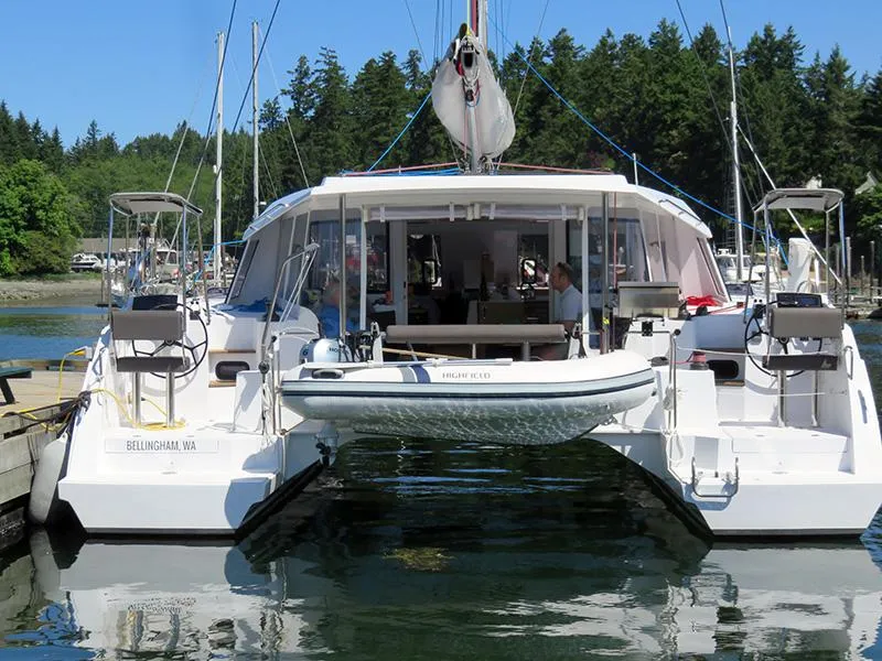 Slide: The Image of 2016 Nautitech 40 Open catamaran docked in a marina with lush green trees in the background. - 16