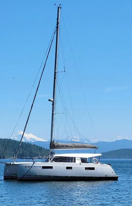 Slide: The Image of 2016 Nautitech 40 Open catamaran sailing on a calm sea with scenic mountain backdrop. - 18