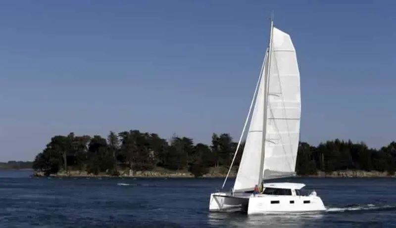 Slide: The Image of Nautitech 40 Open 2016 catamaran sailing near a forested shoreline. - 19