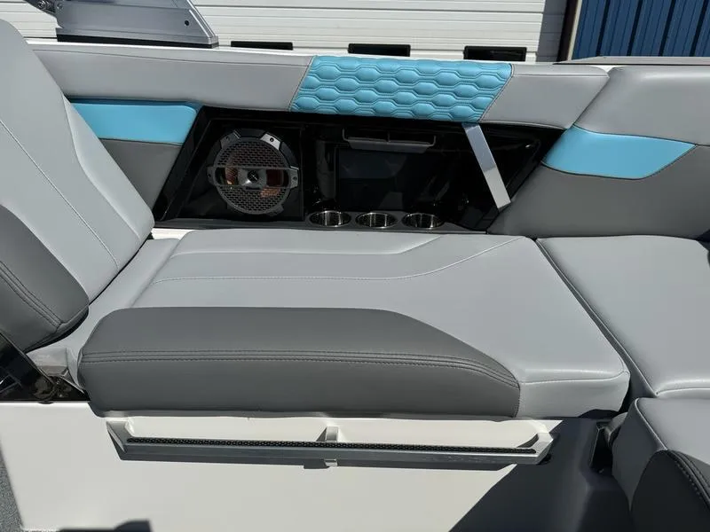 Slide: The Image of 2022 MasterCraft XT24 boat interior with gray and blue seating, speaker, and cup holders. - 18