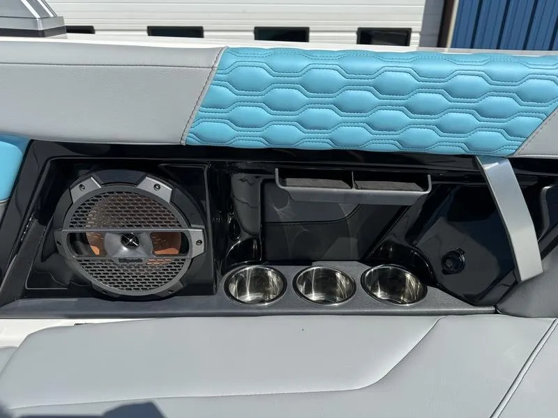 Slide: The Image of 2022 MasterCraft XT24 boat interior with speaker, cup holders, and blue quilted upholstery. - 19