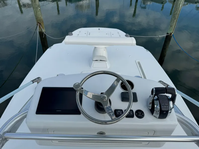 Slide: The Image of Helm of 2020 Invincible 40 Catamaran with steering wheel and controls, docked on calm water. - 12