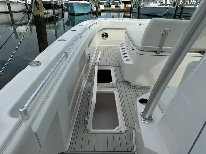 Slide: The Image of 2020 Invincible 40 Catamaran deck with open storage compartments in a marina setting. - 32