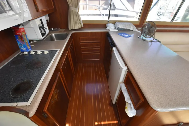 Slide: The Image of 1987 Hatteras SportFish yacht kitchen with stove, sink, and mini-fridge. - 14