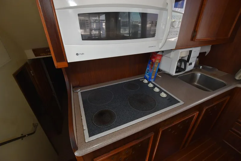 Slide: The Image of 1987 Hatteras SportFish kitchen with stove, microwave, and sink. - 15