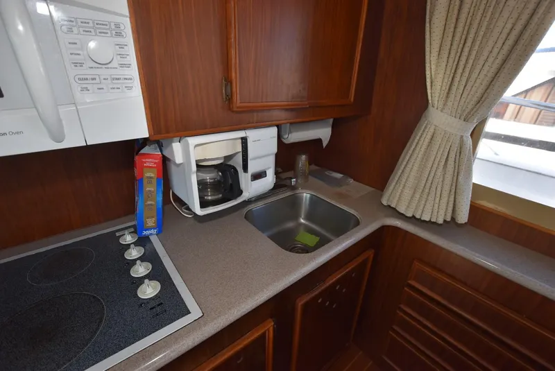 Slide: The Image of 1987 Hatteras SportFish kitchen with stove, sink, coffee maker, and window. - 16