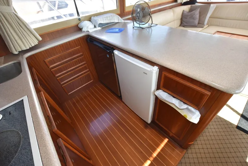 Slide: The Image of 1987 Hatteras SportFish yacht kitchen with wood flooring, mini fridge, and countertop. - 17