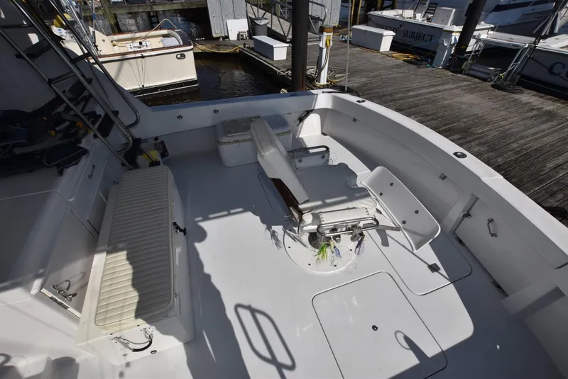 Slide: The Image of 1987 Hatteras SportFish (w/CATS) boat deck with fishing chair and docked boats. - 2