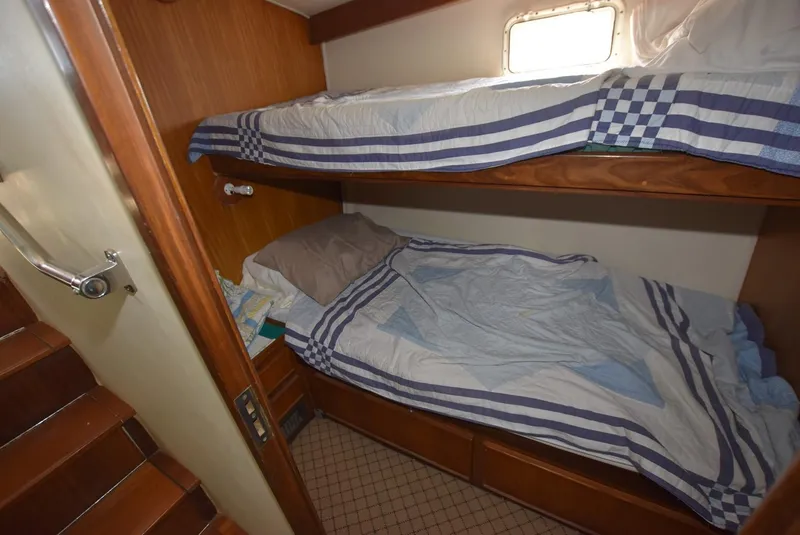 Slide: The Image of 1987 Hatteras SportFish cabin with bunk beds and nautical-themed bedding. - 20